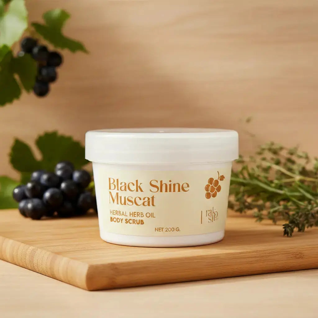 Container of Black Shine Muscat body scrub on a wooden surface with grapes and greenery.