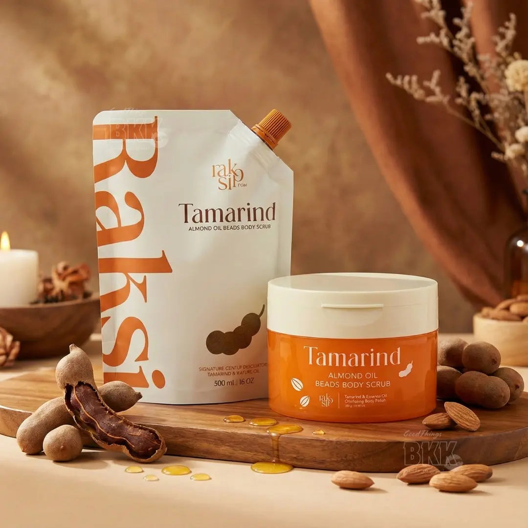 Tamarind almond oil beads body scrub packaging and container on a wooden surface with almonds and a candle.